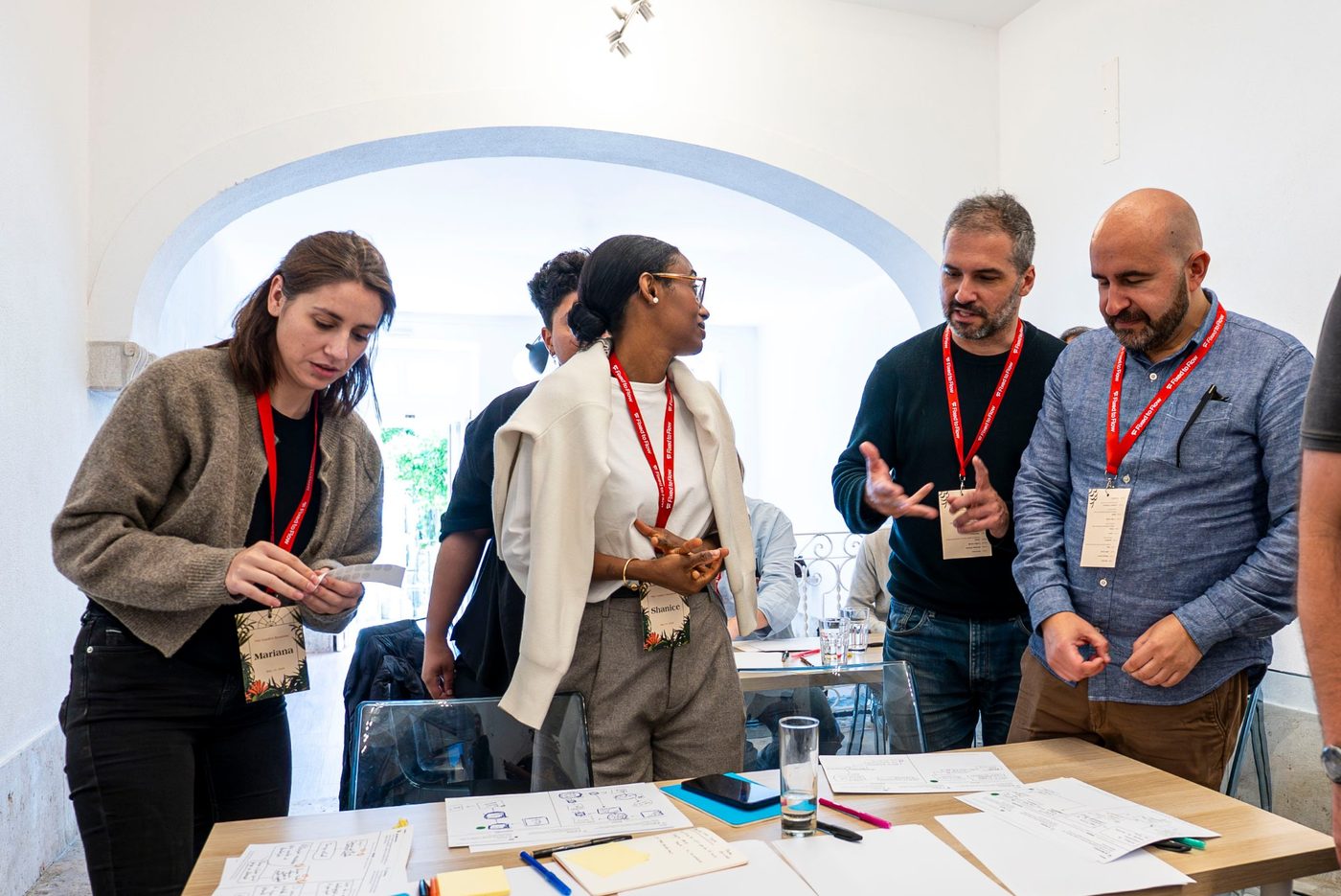 Four participants standing around a table of sketches and sticky notes, talking through their ideas at Garden Sessions