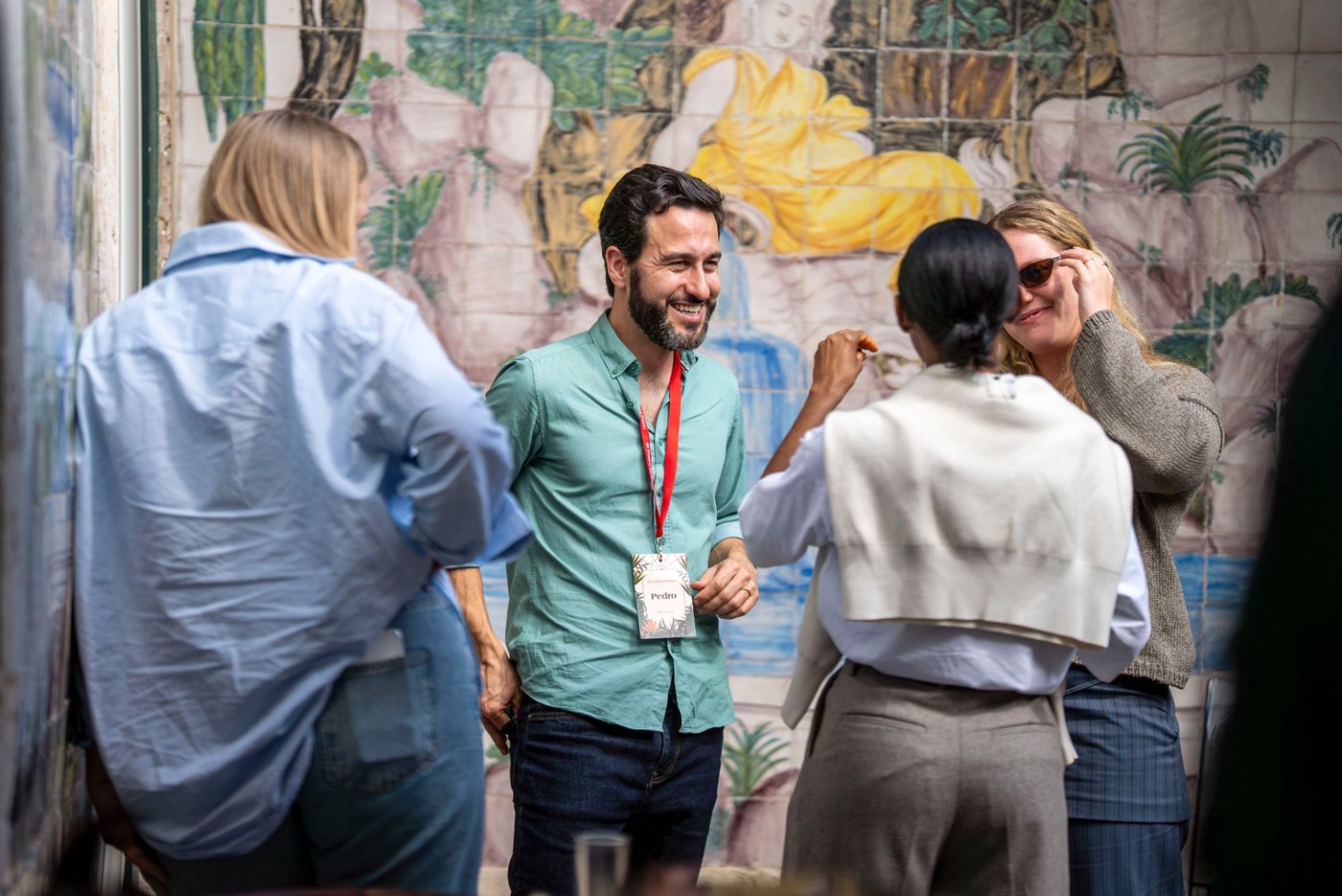 Participants laughing in conversation in front of a painted tile wall at Garden Sessions